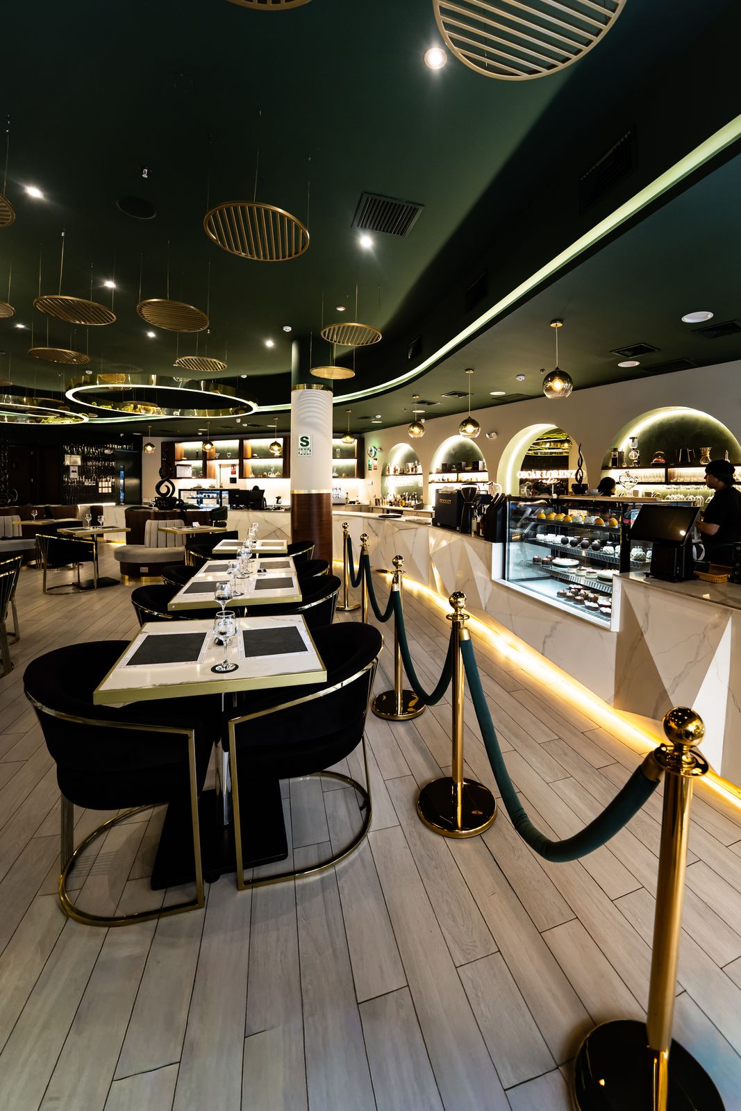 Salón principal de Oscar Lorenzo Café: barra iluminada y techo verde profundo